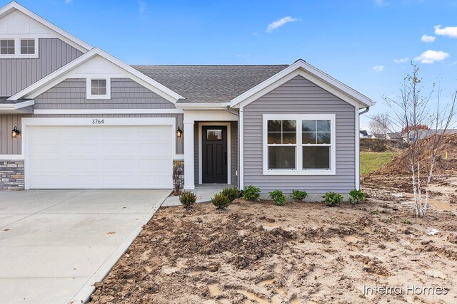 view of front of property with roof with shingles, concrete driveway, and an attached garage