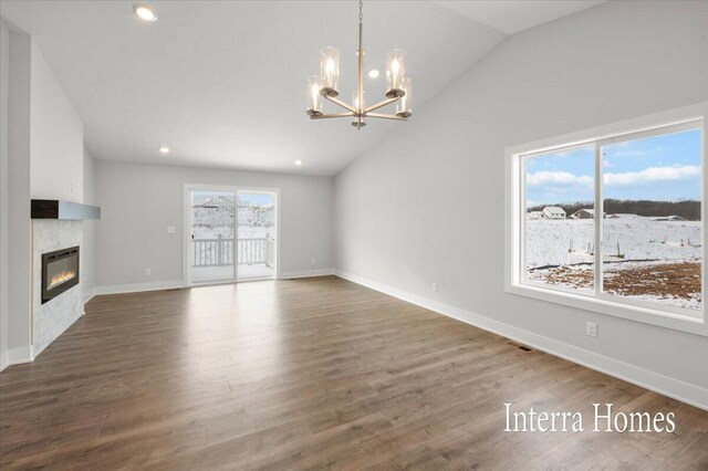 unfurnished living room featuring baseboards, vaulted ceiling, an inviting chandelier, wood finished floors, and a glass covered fireplace