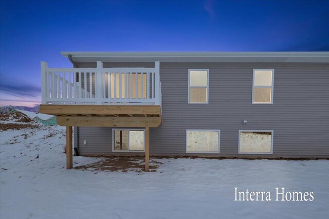 snow covered back of property featuring a wooden deck