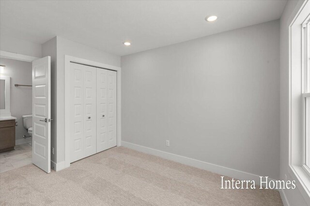 unfurnished bedroom featuring baseboards, recessed lighting, a closet, light colored carpet, and connected bathroom