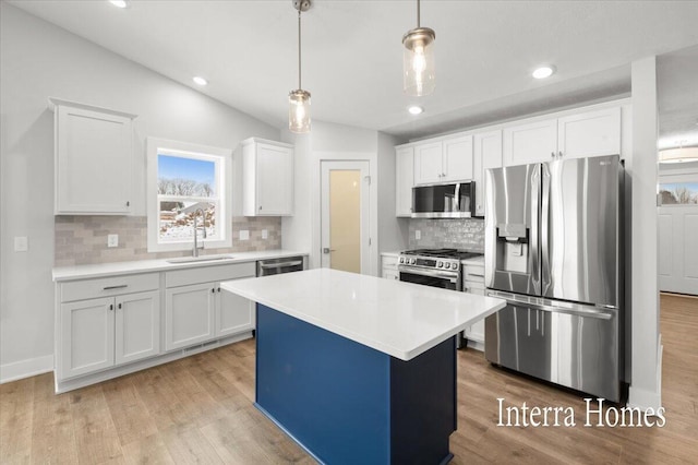 kitchen with appliances with stainless steel finishes, light countertops, light wood-type flooring, and a sink