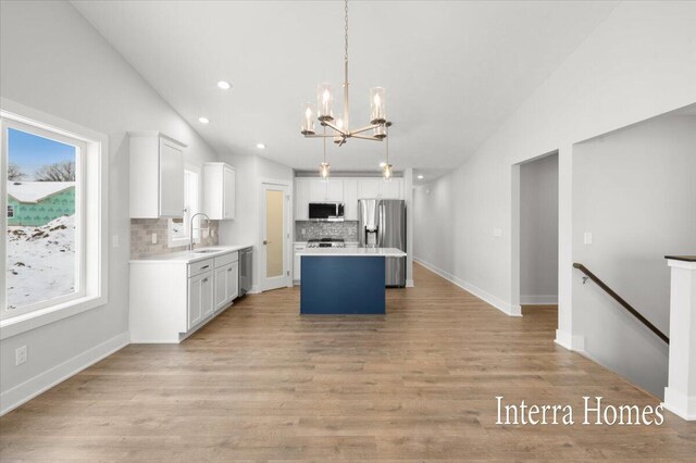 kitchen with white cabinetry, appliances with stainless steel finishes, light wood finished floors, lofted ceiling, and light countertops