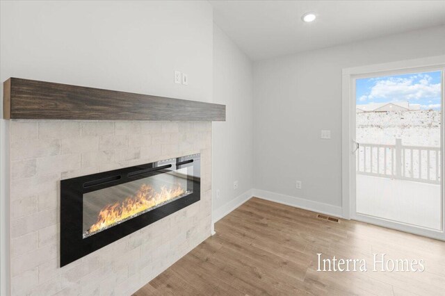 unfurnished living room featuring recessed lighting, a fireplace, baseboards, and wood finished floors