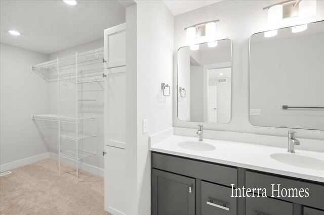 full bath featuring a sink, a walk in closet, baseboards, and double vanity