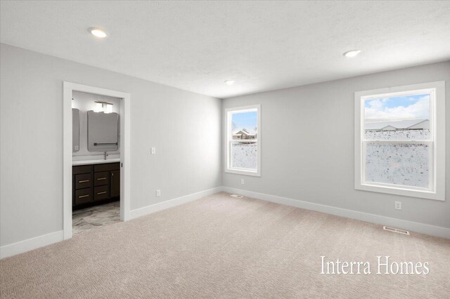 unfurnished bedroom featuring visible vents, ensuite bath, recessed lighting, baseboards, and light colored carpet