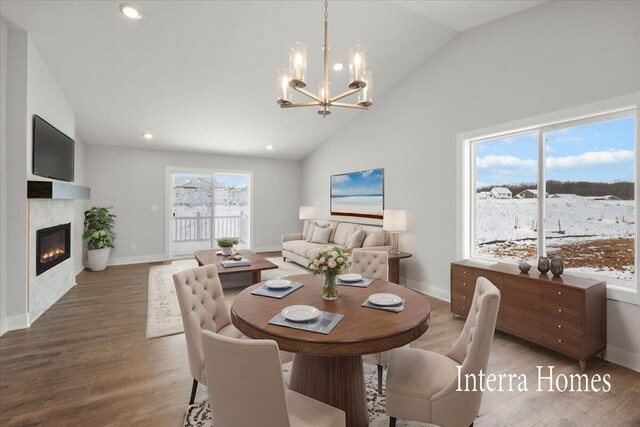 dining room with a chandelier, recessed lighting, wood finished floors, a glass covered fireplace, and high vaulted ceiling