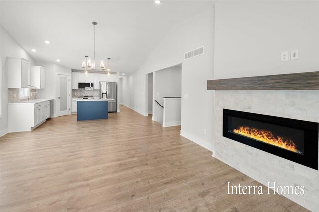 kitchen featuring visible vents, open floor plan, light wood-type flooring, light countertops, and appliances with stainless steel finishes