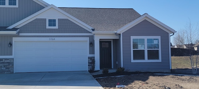 view of front of property with a garage, stone siding, driveway, and a shingled roof