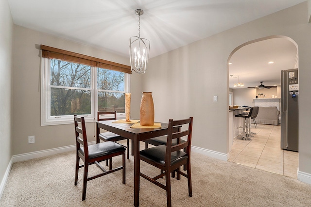 carpeted dining room featuring ceiling fan with notable chandelier