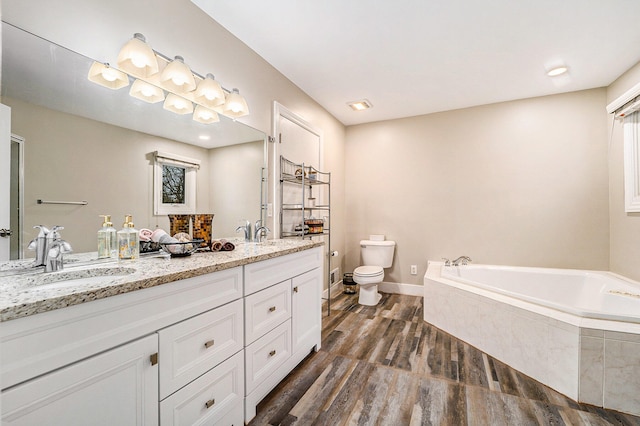 bathroom featuring a relaxing tiled tub, wood-type flooring, vanity, and toilet