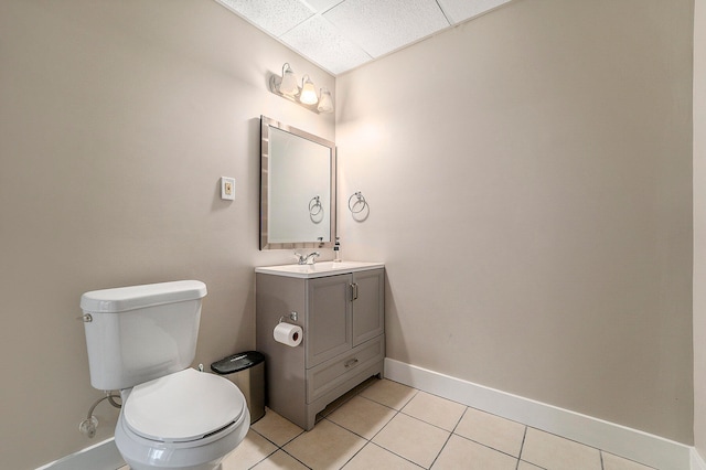 bathroom featuring toilet, vanity, a drop ceiling, and tile patterned floors