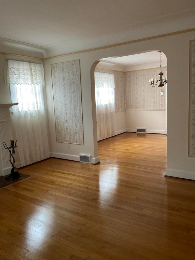 unfurnished room with hardwood / wood-style flooring and a notable chandelier