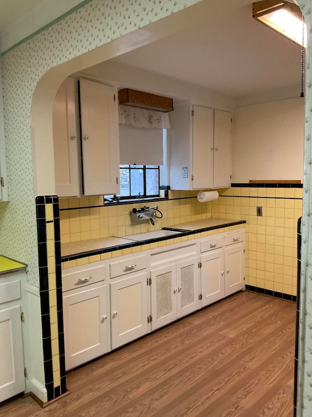 kitchen featuring tile walls, sink, light hardwood / wood-style floors, and white cabinets