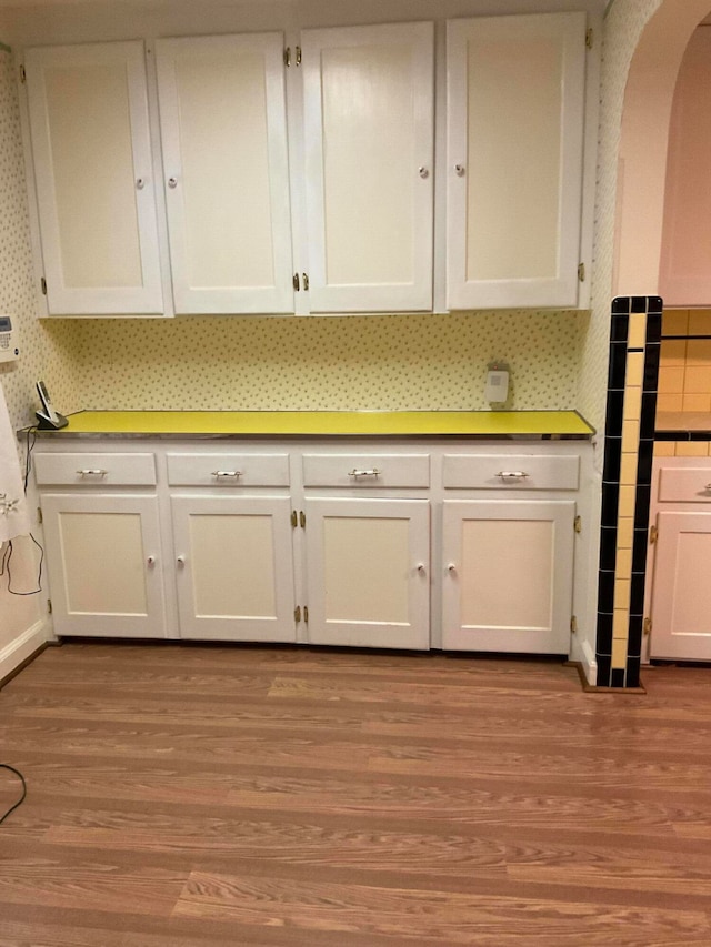 kitchen with white cabinets, decorative backsplash, and light hardwood / wood-style flooring