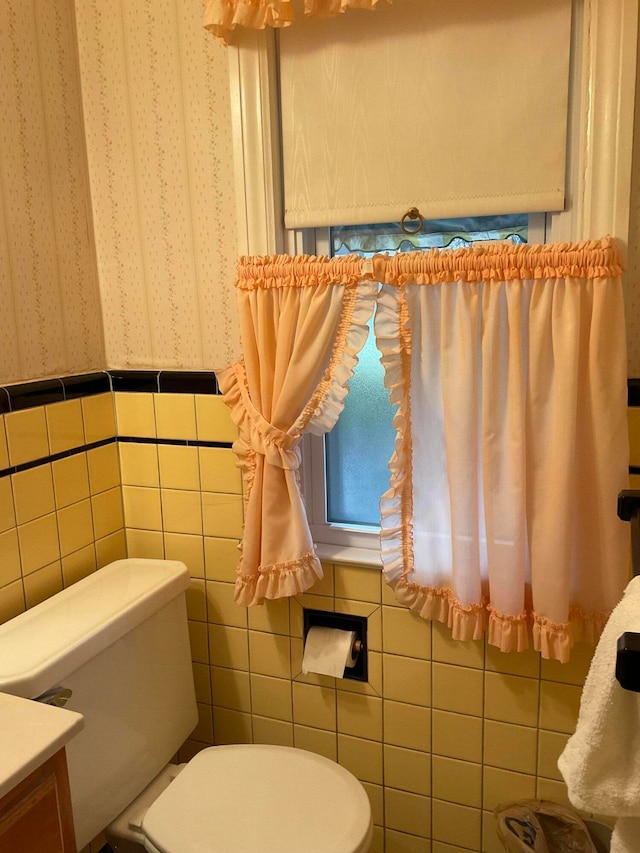 bathroom featuring toilet, vanity, and tile walls