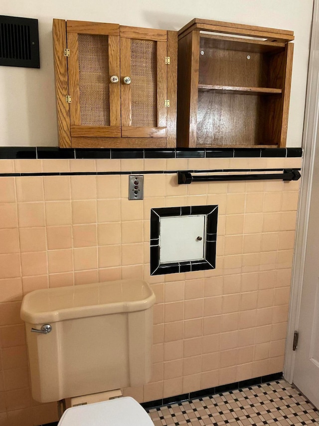 bathroom with toilet, tile walls, and tile patterned floors