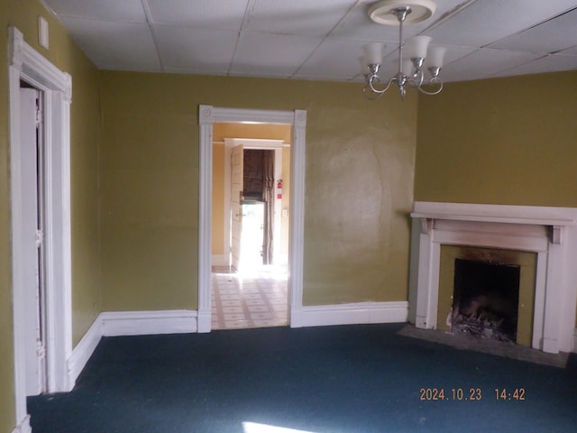 unfurnished living room featuring a drop ceiling and a chandelier