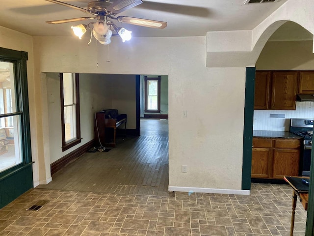 kitchen with tasteful backsplash, exhaust hood, hardwood / wood-style flooring, stainless steel range oven, and ceiling fan