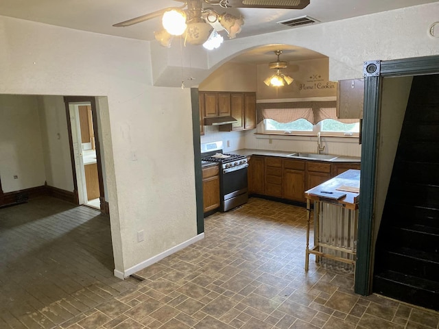 kitchen with hanging light fixtures, sink, stainless steel gas range oven, and ceiling fan