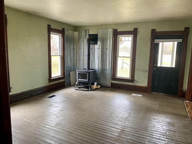 unfurnished living room with a wood stove, plenty of natural light, and wood-type flooring