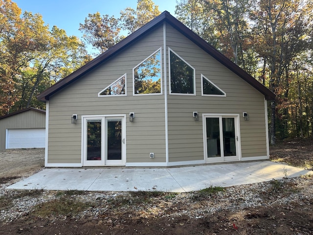 rear view of property featuring a garage, an outdoor structure, french doors, and a patio area