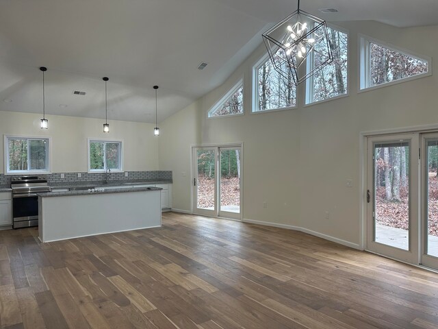 kitchen featuring stainless steel electric stove, white cabinetry, decorative light fixtures, and hardwood / wood-style flooring