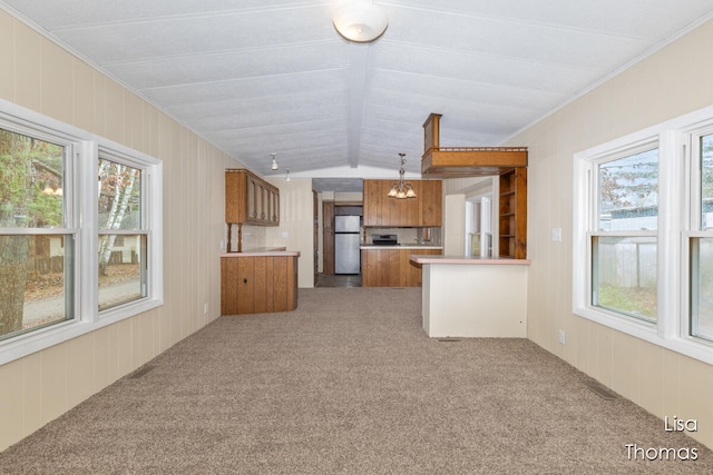 kitchen with pendant lighting, a wealth of natural light, vaulted ceiling, and stainless steel fridge