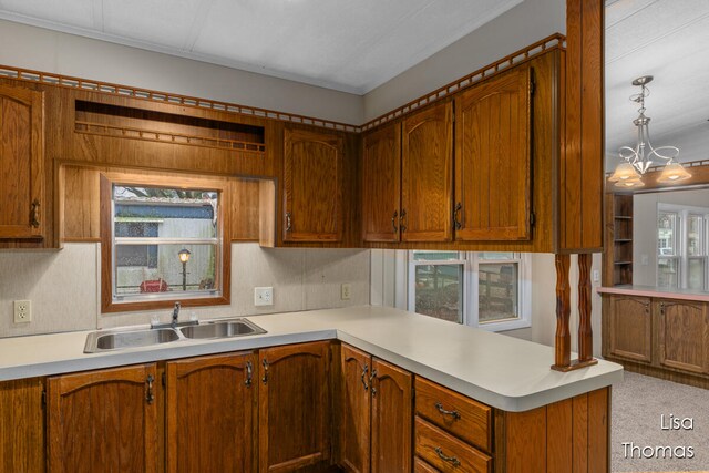 kitchen with pendant lighting, sink, an inviting chandelier, and kitchen peninsula