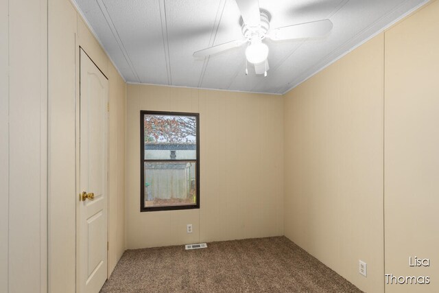 spare room featuring ornamental molding, carpet floors, and ceiling fan