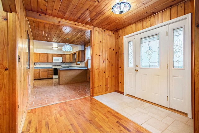 entryway featuring light wood-type flooring, beamed ceiling, wooden walls, and wooden ceiling