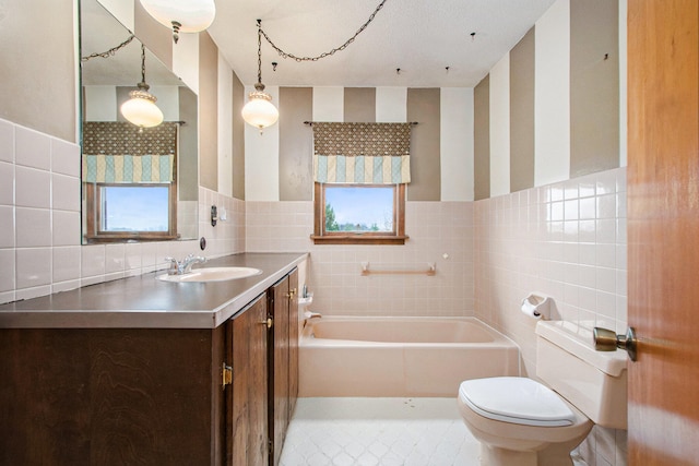 bathroom with a wealth of natural light, vanity, toilet, a bathtub, and tile walls