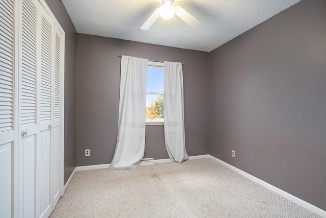 unfurnished bedroom featuring ceiling fan, a textured ceiling, a closet, and carpet floors