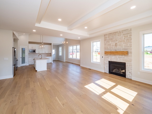 unfurnished living room featuring light wood-type flooring, a fireplace, and an inviting chandelier