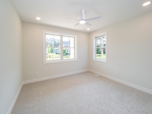 empty room with a wealth of natural light, light carpet, and ceiling fan