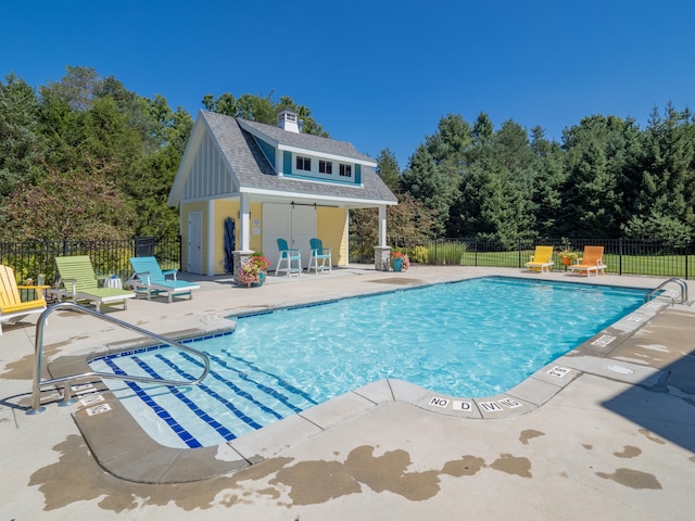 view of swimming pool featuring an outbuilding and a patio