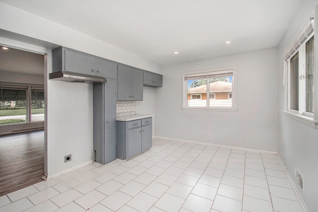 kitchen with light tile patterned flooring, gray cabinetry, and backsplash