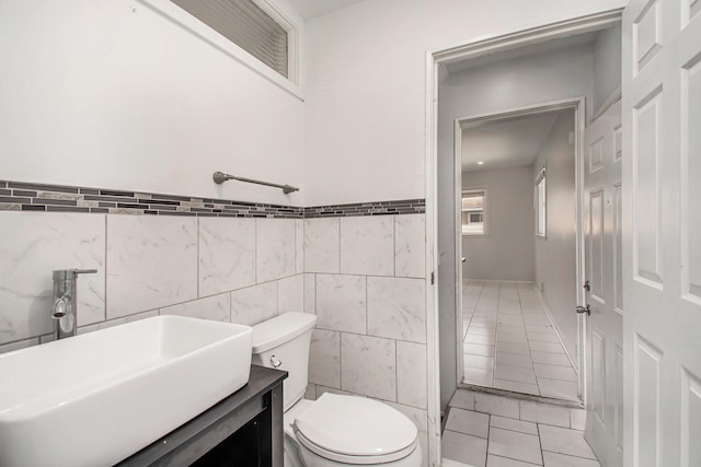 bathroom featuring tile walls, toilet, vanity, and tile patterned floors