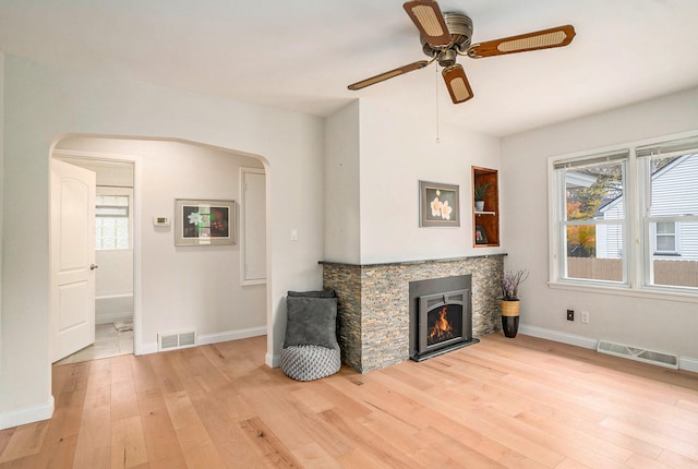 living room with a fireplace, a wealth of natural light, ceiling fan, and light hardwood / wood-style flooring