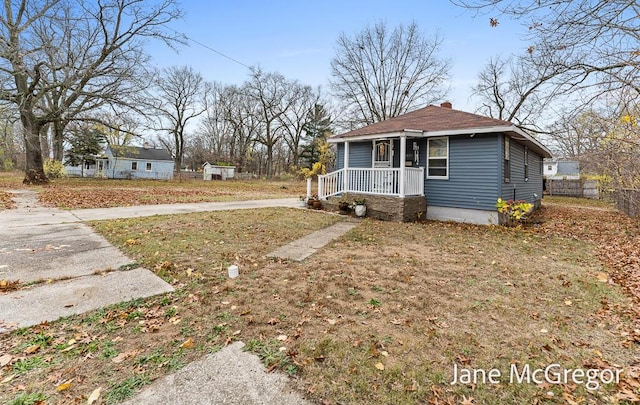 bungalow-style house featuring covered porch and a front yard