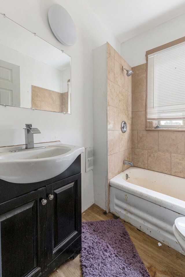 full bathroom with hardwood / wood-style flooring, vanity, toilet, and tiled shower / bath combo