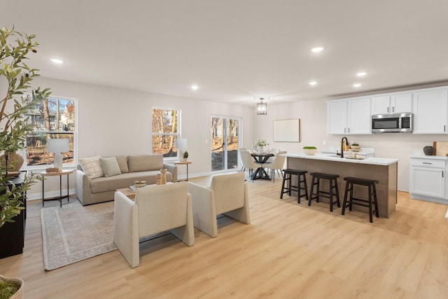 living room featuring plenty of natural light, sink, and light hardwood / wood-style floors