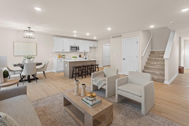 living room with sink, light hardwood / wood-style flooring, and a chandelier