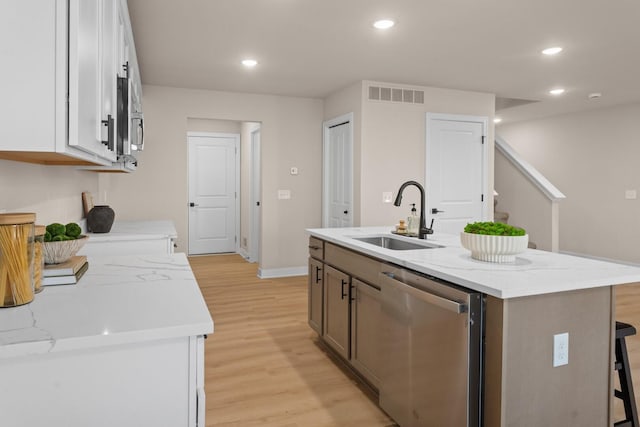 kitchen with sink, dishwasher, an island with sink, and white cabinets