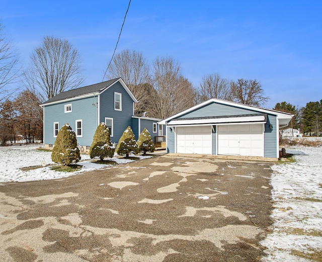 view of snow covered exterior with a garage and an outbuilding