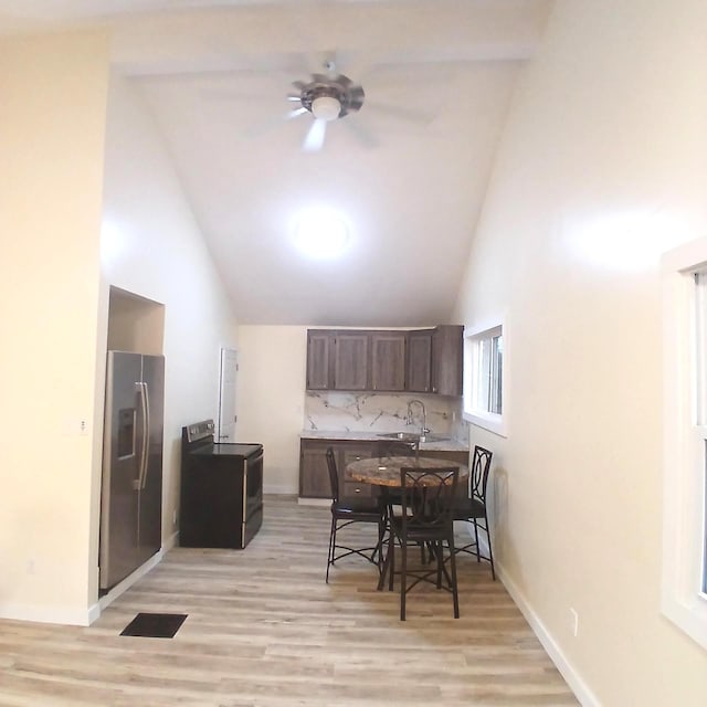 dining space featuring light wood-type flooring, ceiling fan, sink, and high vaulted ceiling