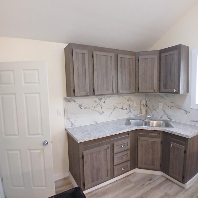 kitchen with decorative backsplash, sink, dark brown cabinets, and light hardwood / wood-style floors