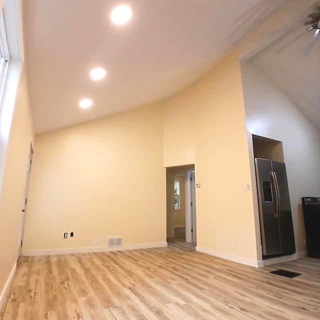 unfurnished living room with light wood-type flooring, ceiling fan, and high vaulted ceiling