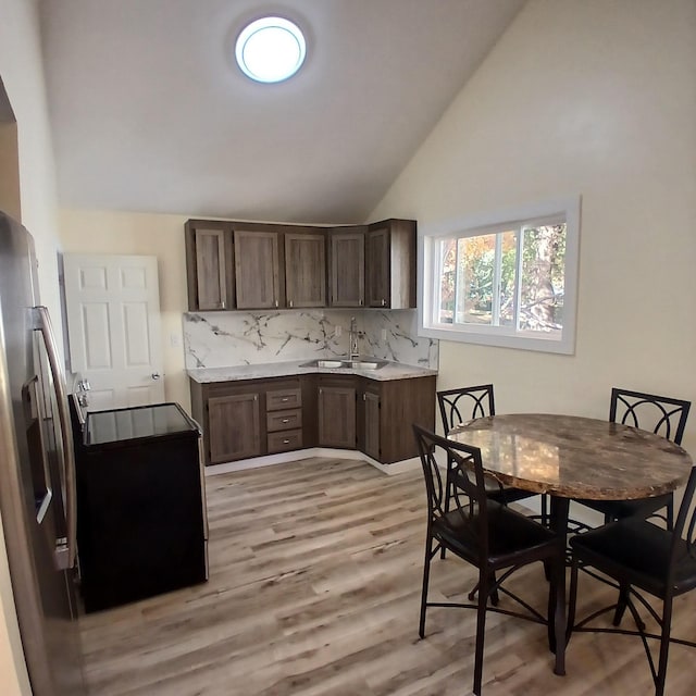 kitchen featuring dark brown cabinetry, light hardwood / wood-style floors, sink, high vaulted ceiling, and electric stove