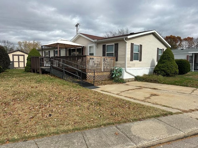 view of front of home with a deck, a front yard, and a storage shed