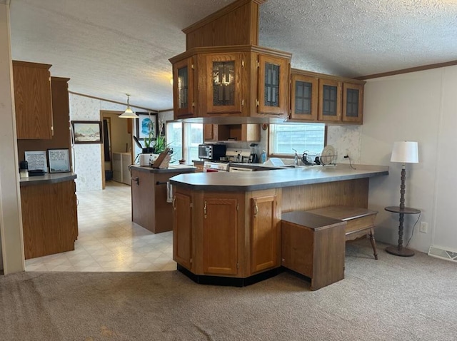 kitchen with ornamental molding, a textured ceiling, light carpet, hanging light fixtures, and kitchen peninsula